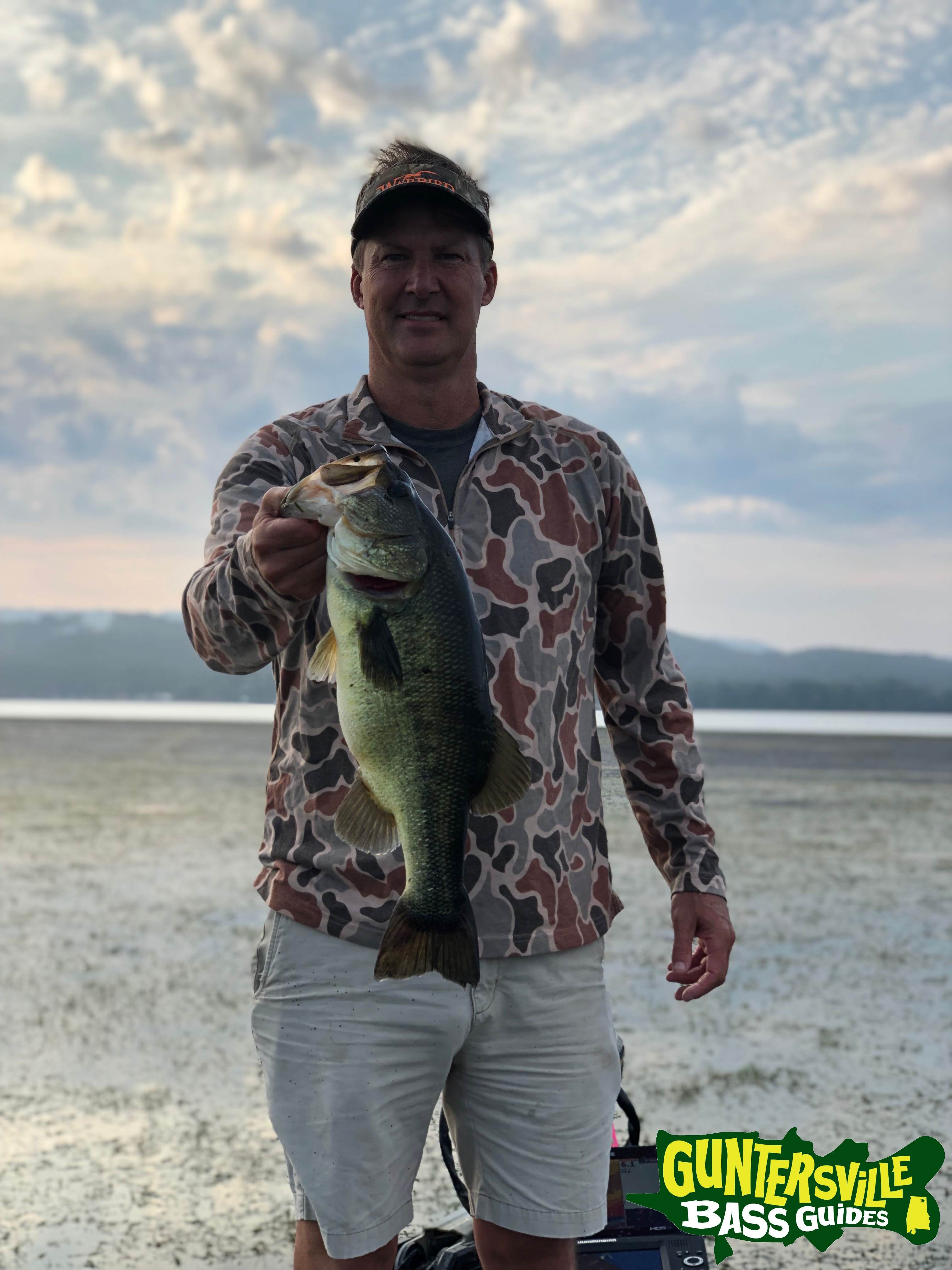 Guntersville Bass Guides client holding a bass pulled from a thick Lake Guntersville grass mat