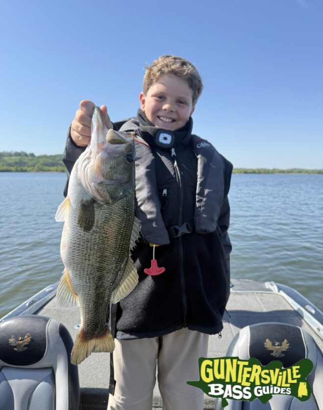Young angler holding a big bass from a spring time fishing trip on lake guntersville
