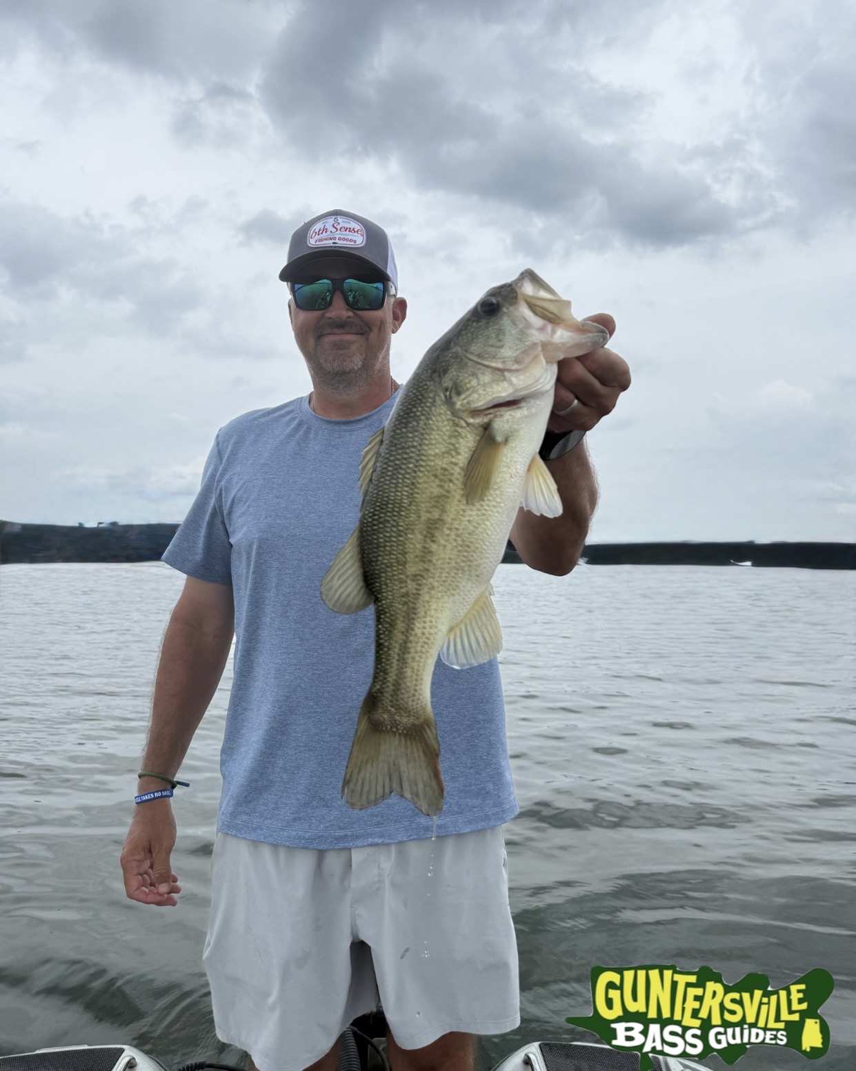 Angler holding a big bass from Lake Guntersville while Bass fishing with guntersville bass guides